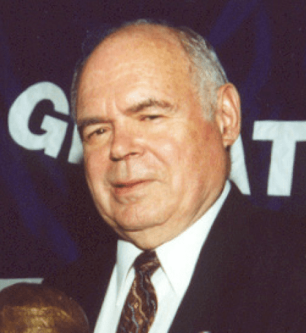 A man in suit and tie standing next to a blue wall.