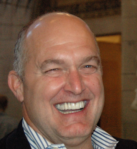 A man with bald head and white teeth smiling.