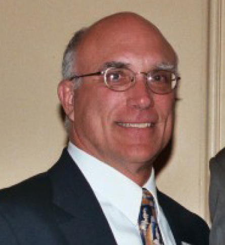 A man in suit and tie smiling for the camera.