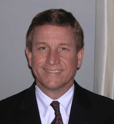 A man in suit and tie smiling for the camera.