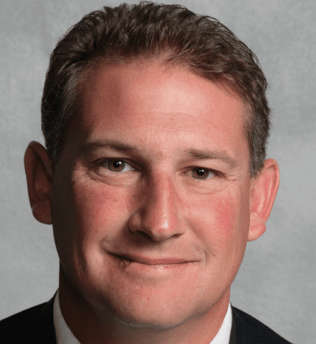 A man in suit and tie smiling for the camera.