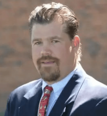 A man in a suit and tie standing outside.