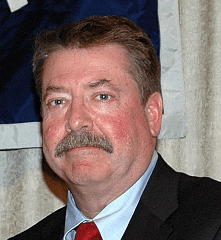 A man with a mustache wearing a suit and tie.