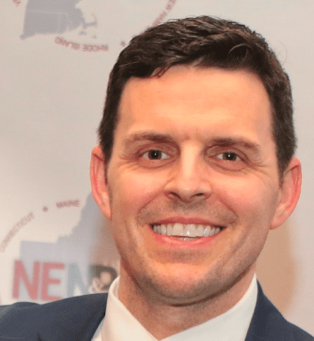 A man in suit and tie smiling for the camera.