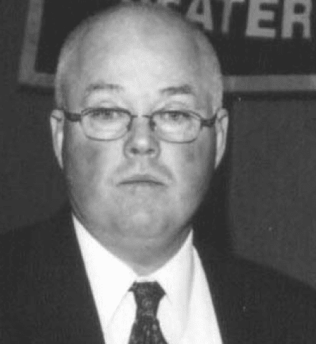 A man with glasses and bald head wearing a suit.