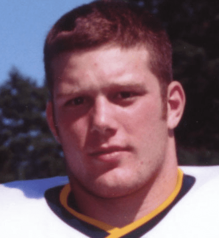 A close up of a football player with his head turned.