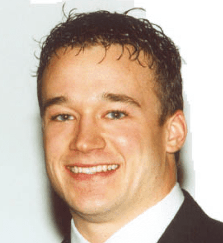 A man in suit and tie smiling for the camera.