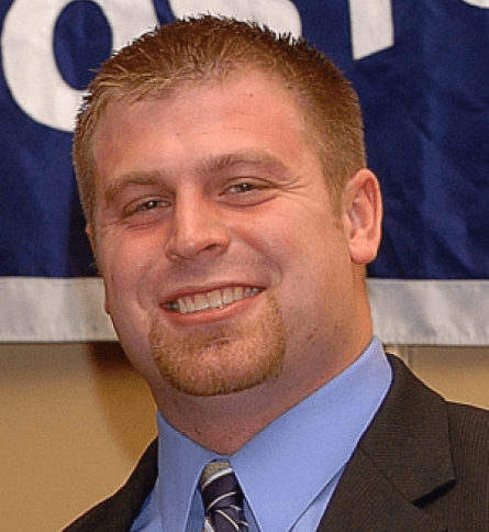 A man in suit and tie smiling for the camera.