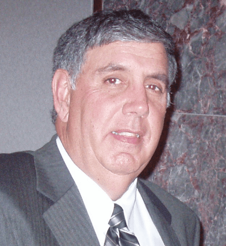 A man in a suit and tie standing next to a wall.