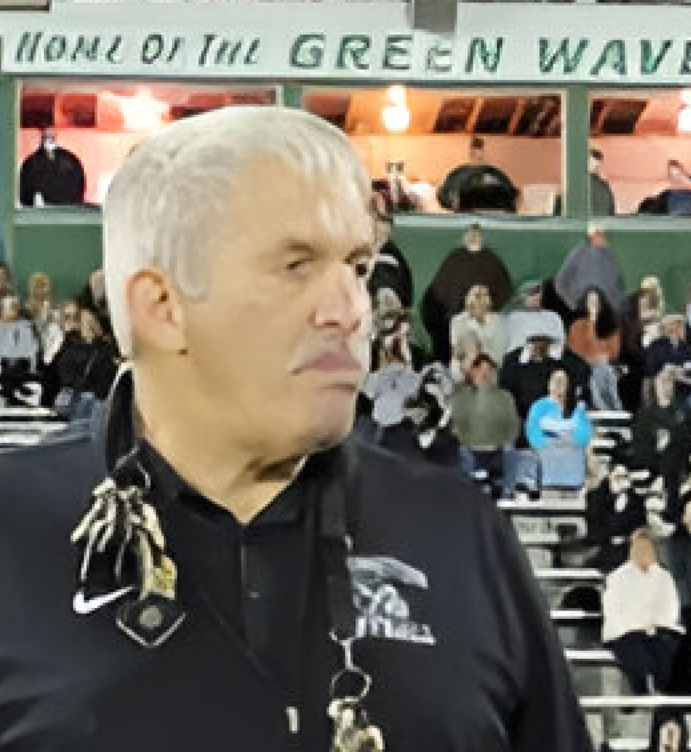 A man in black shirt and white hair standing next to crowd.