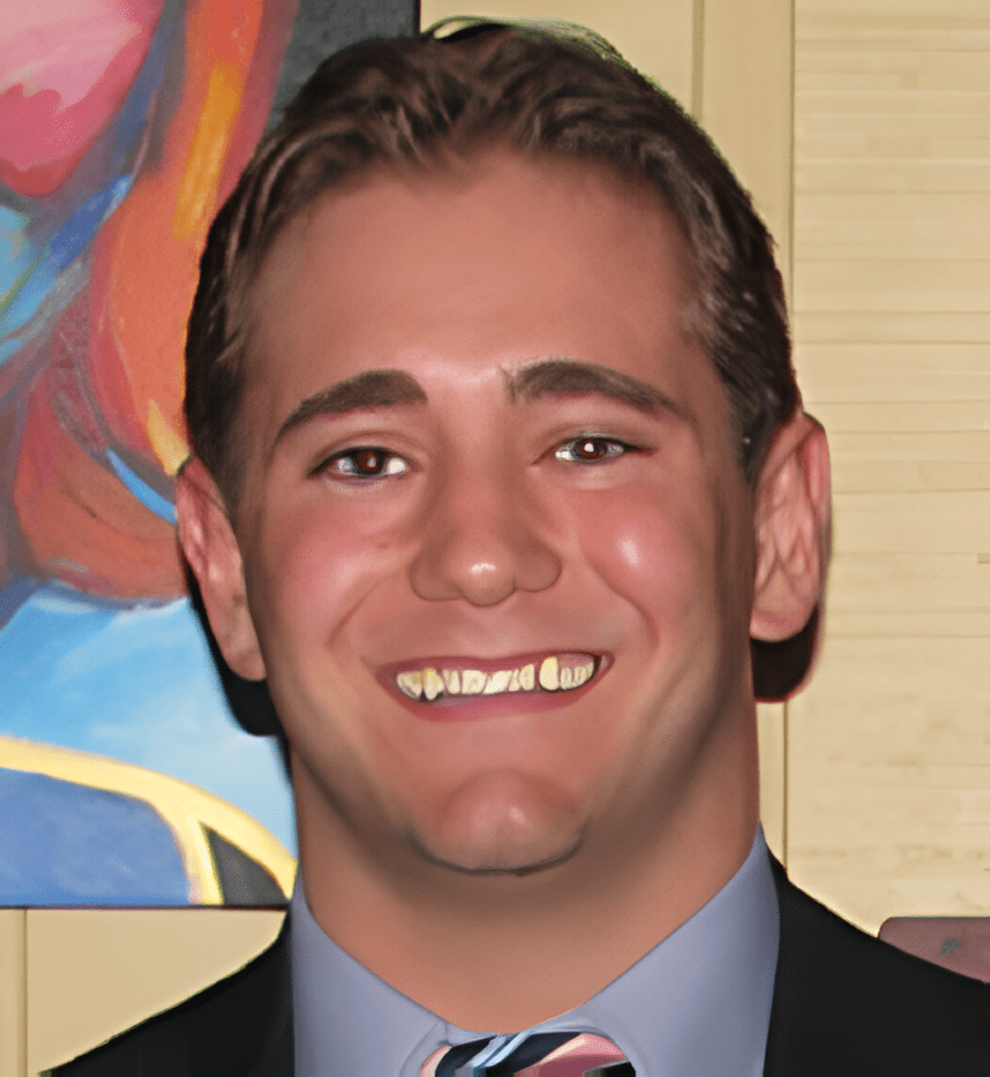 A man in suit and tie smiling for the camera.