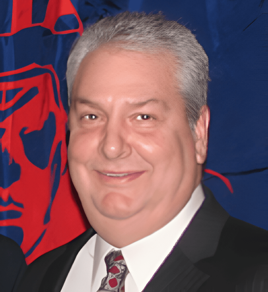 A man in suit and tie standing next to a flag.