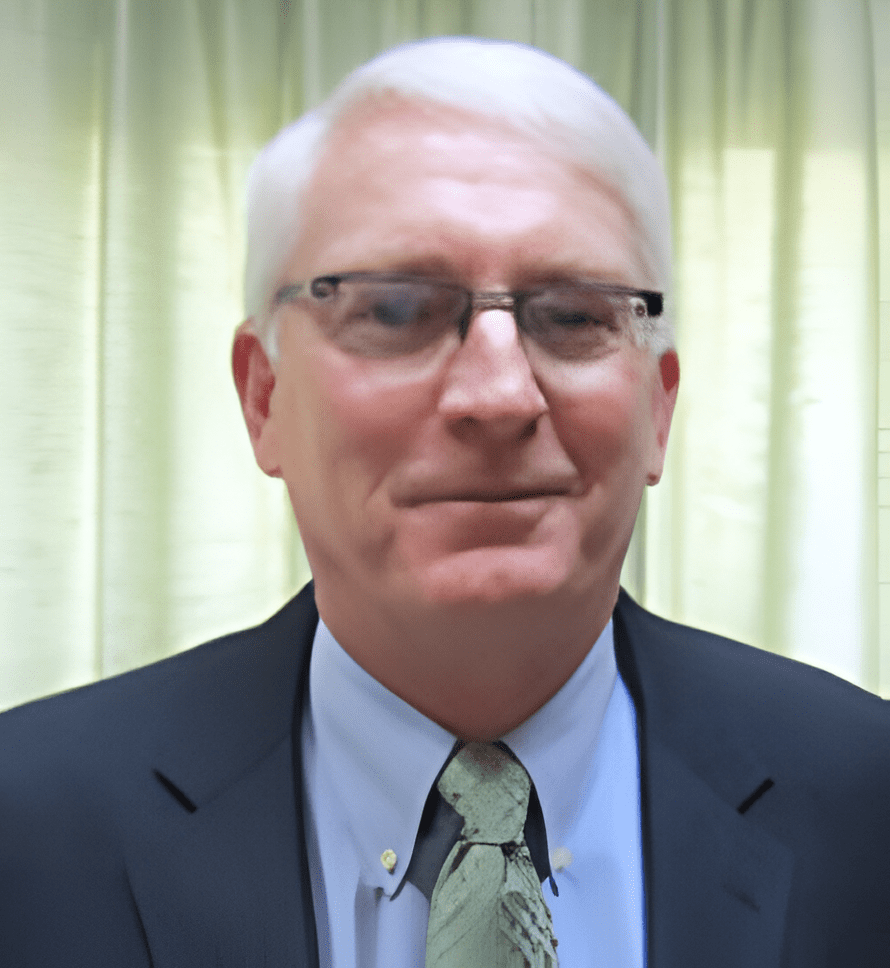 A man with white hair and glasses wearing a suit.