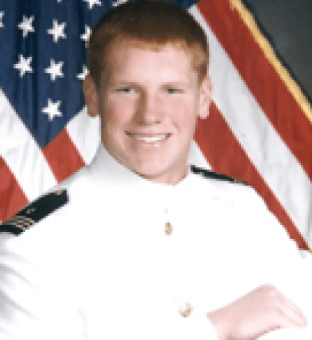 A man in uniform standing next to an american flag.