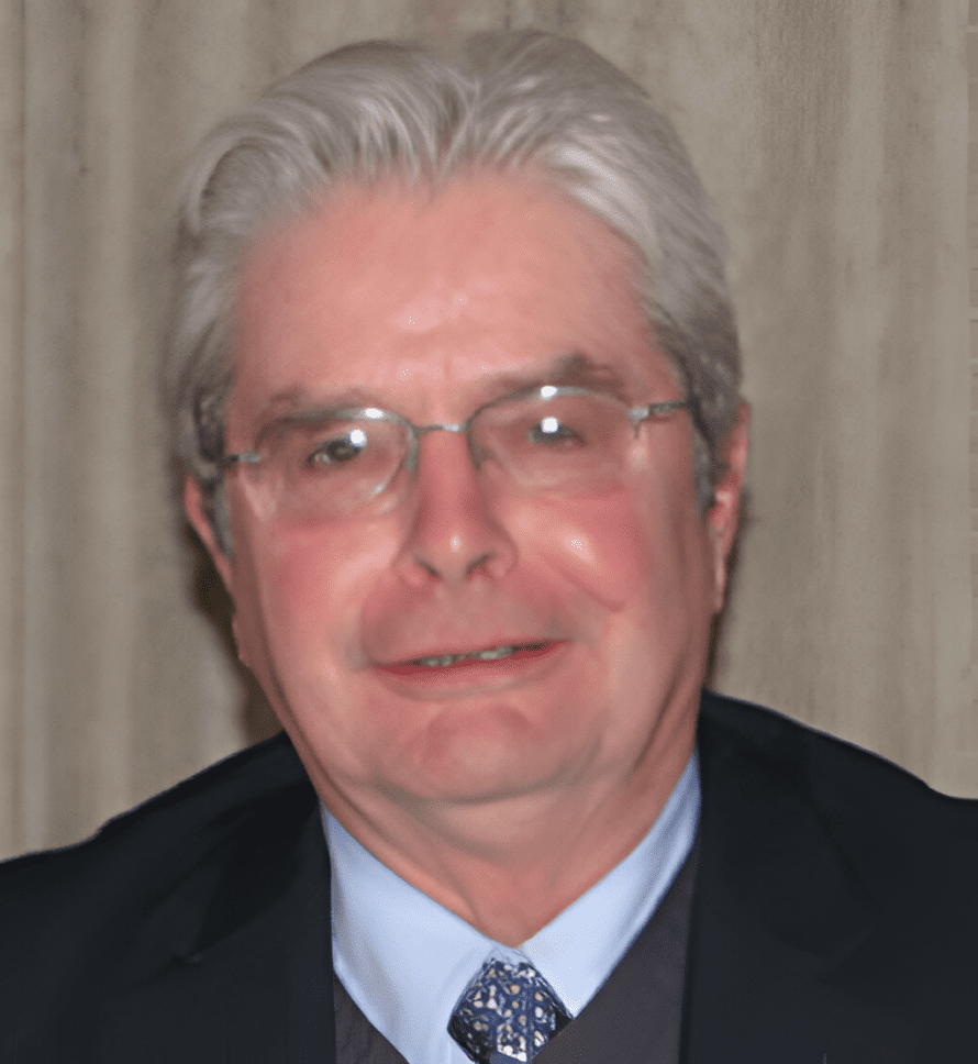 A man with white hair and glasses wearing a suit.