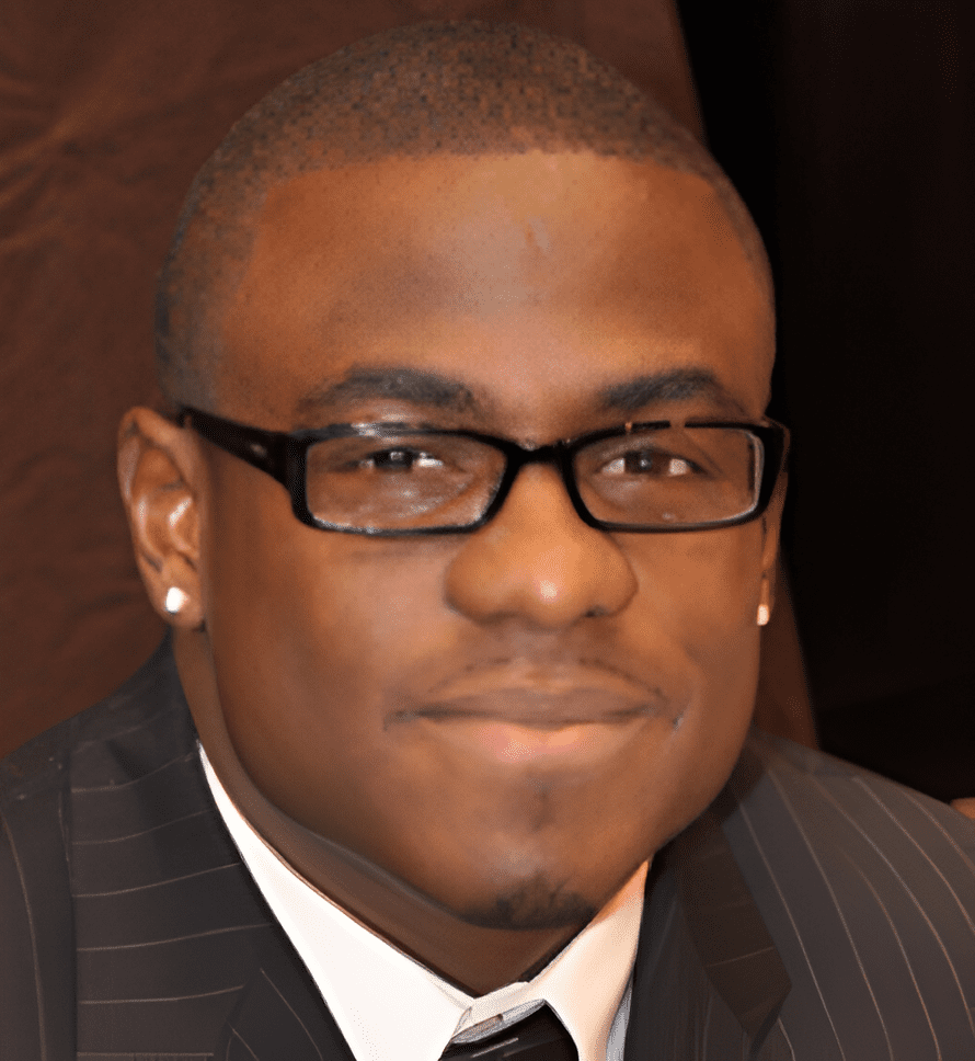 A man in glasses and suit smiling for the camera.