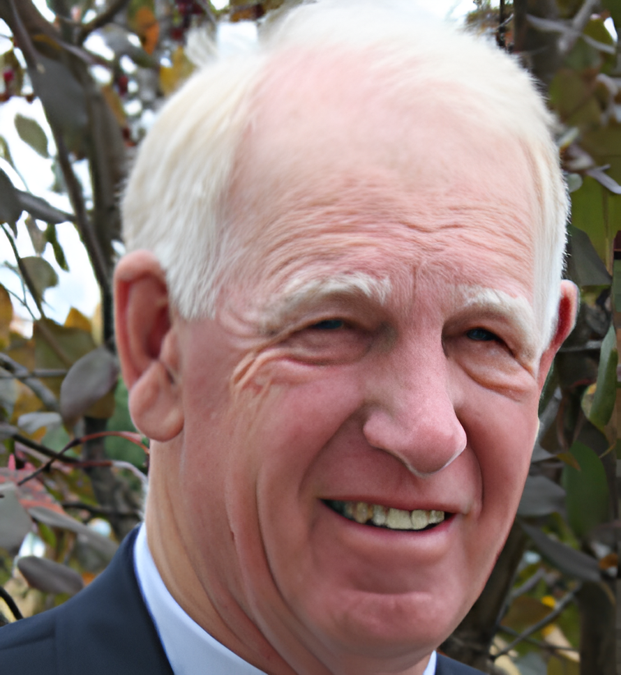 A man with white hair and wearing a suit.