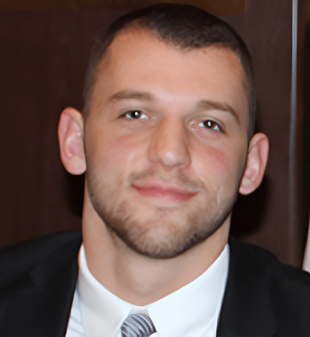 A man in suit and tie smiling for the camera.