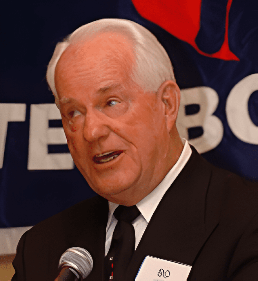 A man in suit and tie speaking at a microphone.