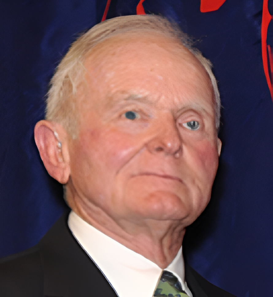 A man in suit and tie with white hair.