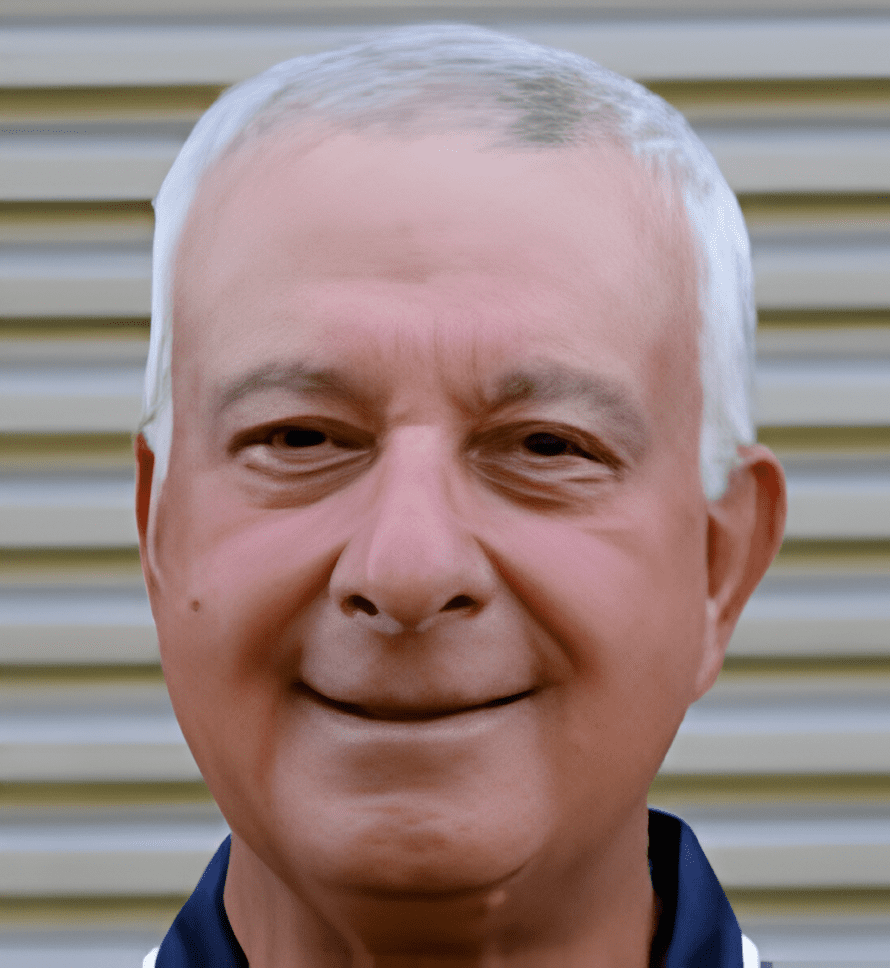 A man with white hair and blue shirt smiling.