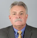 A man with gray hair and a mustache wearing a suit.