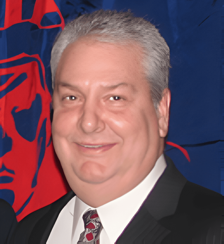 A man in suit and tie next to a flag.