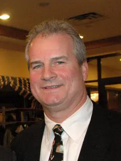 A man in a suit and tie smiling for the camera.